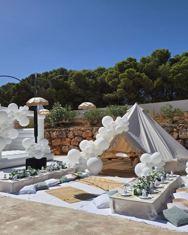 Montaje de boda en blanco con castillo hinchable, carpa tipi y mesas de pícnic en Mijas — El Baúl de Zoé